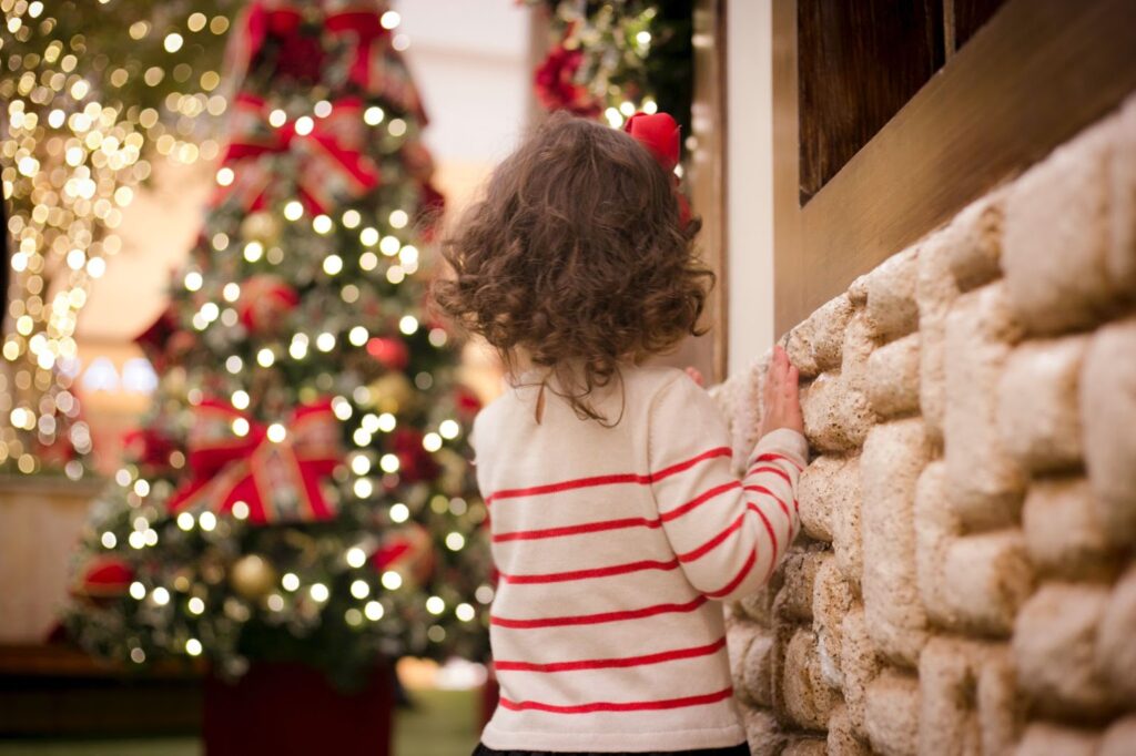 A young child standing near a Christmas tree.
