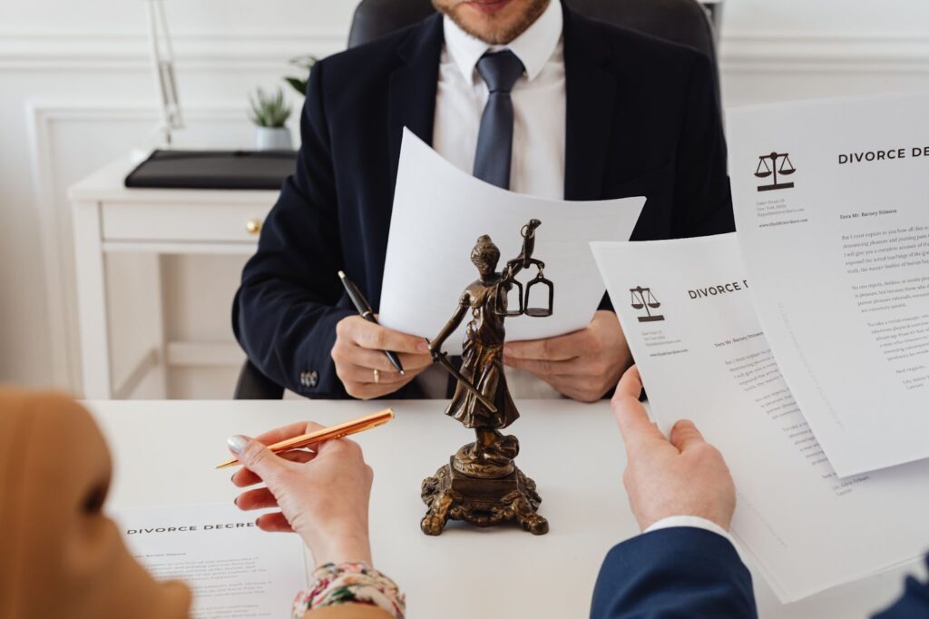 A photo of a couple in front of a divorce attorney with divorce decrees in their hands and being signed.